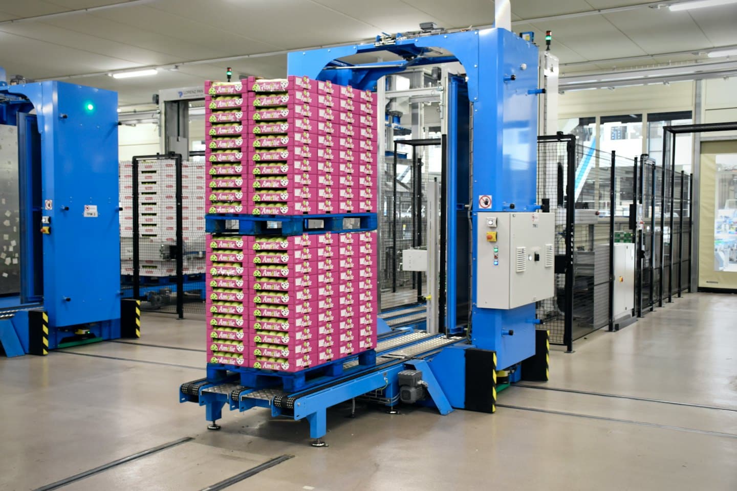 Blue industrial machine packing pink boxes in a factory.