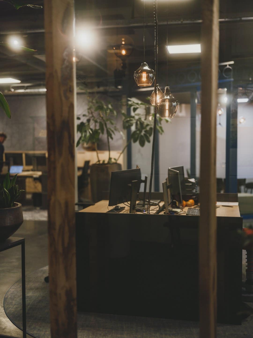Modern office workstation with dual monitors and plants.